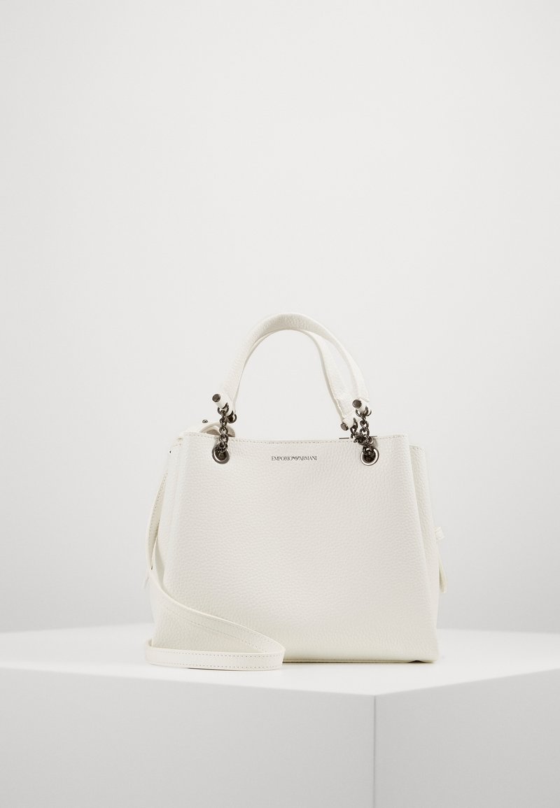 Vit läderhandväska med en strukturerad design, topphandtag och en avtagbar axelrem. Märkbara metalldetaljer och varumärkesprägling.