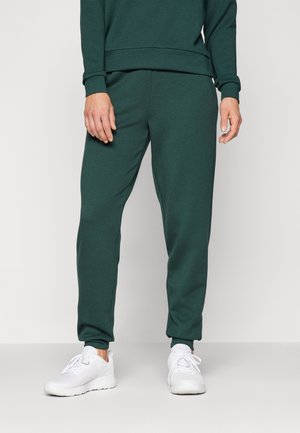 Donkergroene sweatpants met een trekkoord taille, taps toelopende benen en elastische boorden, gecombineerd met witte sportschoenen. Glad stofgevoel.