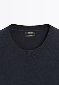 Maglione in cashmere blu navy scuro con collo a girocollo a coste. Tessuto morbido e design minimalista, con etichetta che riporta le informazioni sul marchio e sul materiale.