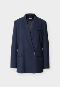 Στενή μπλε σκούρα σακάκι με μία κουμπωτή κούμπωμα, γιακάδες με σχισμές και μπροστινές τσέπες με καπάκι, εμφανιζόμενο σε φωτεινό φόντο.