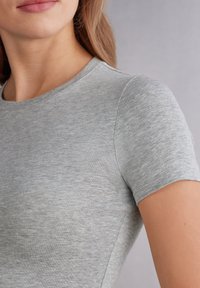 Šedé bavlněné tričko s kulatým výstřihem a krátkými rukávy. Soft textura s hladkým, mírně melírovaným povrchem. Čisté švy a jednoduchý design.