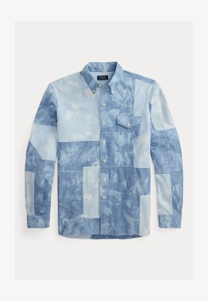 Koszula na długi rękaw zapinana na guziki z wzorem patchworkowym w różnych odcieniach jasnego i średniego denimu w kolorze niebieskim, wyposażona w kieszeń na piersi i kołnierzyk zapinany na guziki.