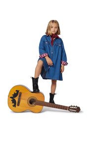 Džinsinė suknelė su rožinėmis languotomis rankovėmis, bordo šalikėlis, juodi ilgi batai ir akustinė gitara su dekoratyviniais akcentais.