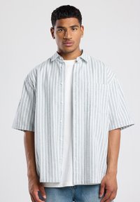 Short-sleeve button-up shirt in white with vertical blue stripes. Features a chest pocket and relaxed fit, made from a lightweight fabric.