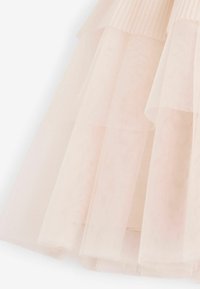 Tissu en tulle rose pâle superposé avec une ceinture en maille côtelée, montrant une texture douce et fluide avec des plis délicats.