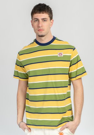 Young man with short hair wearing a yellow, green, white, and navy striped T-shirt with a small logo patch on chest.