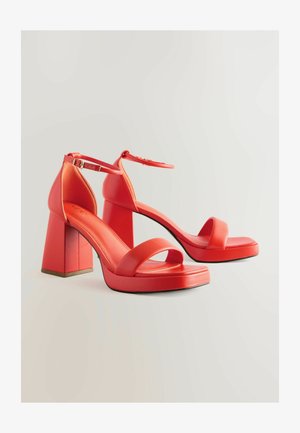Červené sandály na vysokém podpatku s širokým popruhem přes prsty a nastavitelným kotníkovým popruhem. Hladký, lesklý povrch.