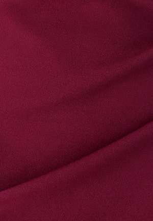 Tessuto borgogna con una consistenza morbida e liscia. Il materiale presenta una leggera lucentezza e presenta drappeggi sottili, creando pieghe delicate.
