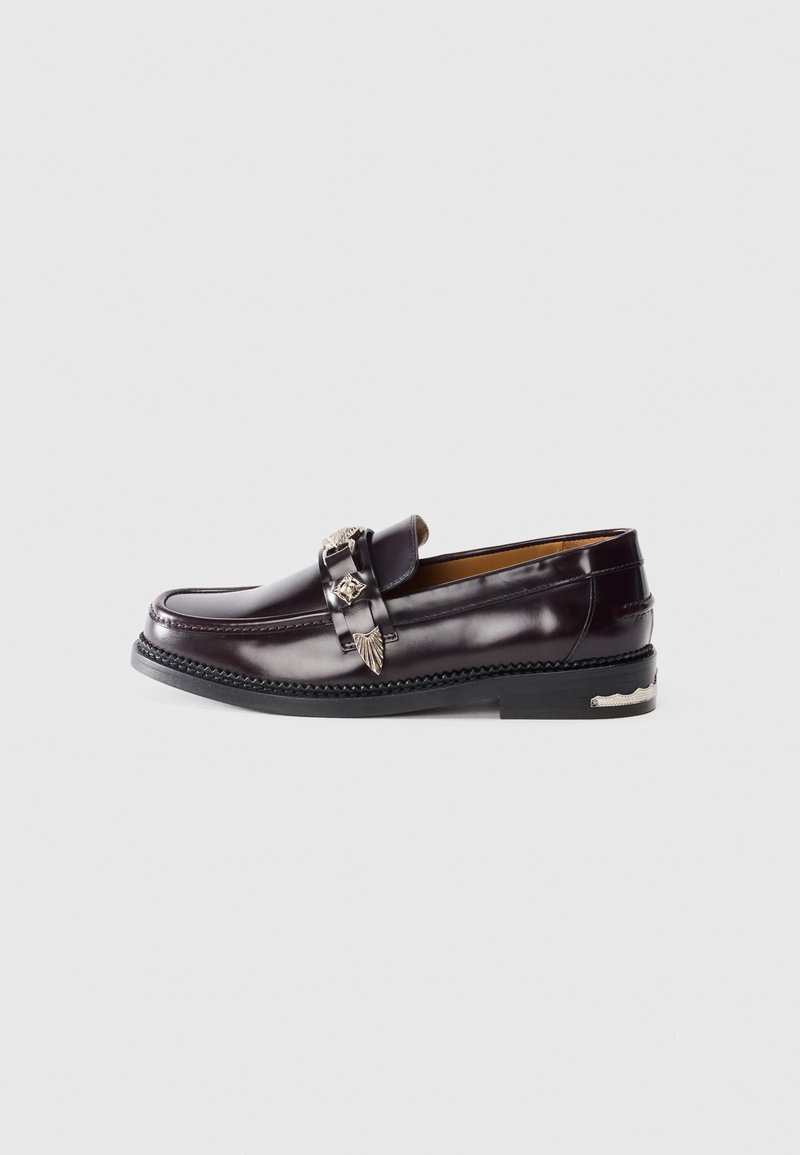 Dark burgundy leather loafer with stitched detailing, decorative metal hardware, and a textured black sole. Classic design with a rounded toe.