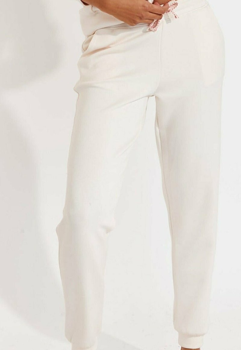 Cremefarbene Jogginghosen aus weichem Material mit einem elastischen Bund und pinkem Kordelzug, seitlichen Taschen und gerippten Bündchen.