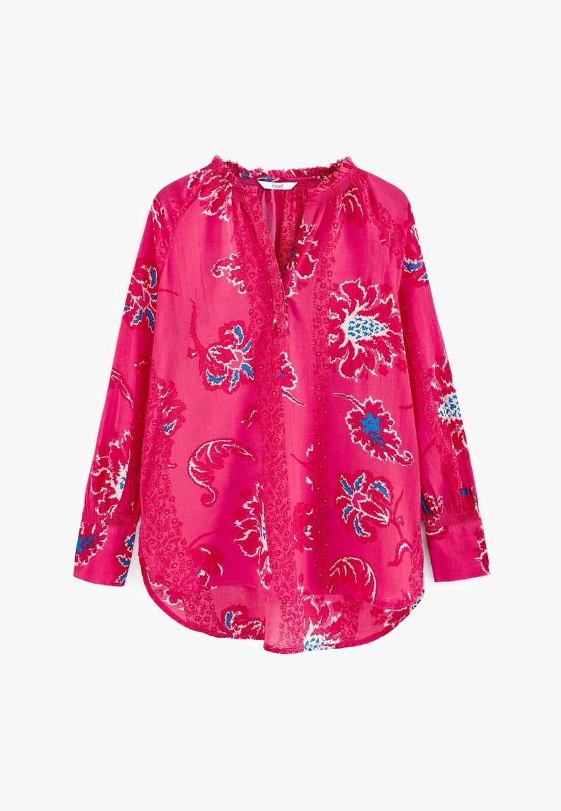 Blouse rose à manches longues avec motifs floraux bleus et blancs, encolure ronde avec léger volant et détails de boutons sur le devant.