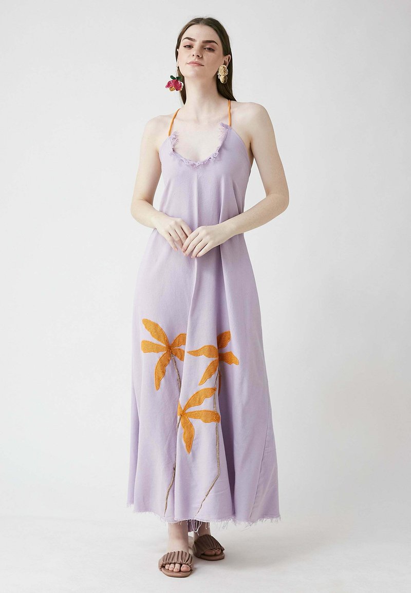 Robe maxi lavande avec col à volants, broderie florale orange, et ourlet à franges ; associé à des sandales brunes en texture.