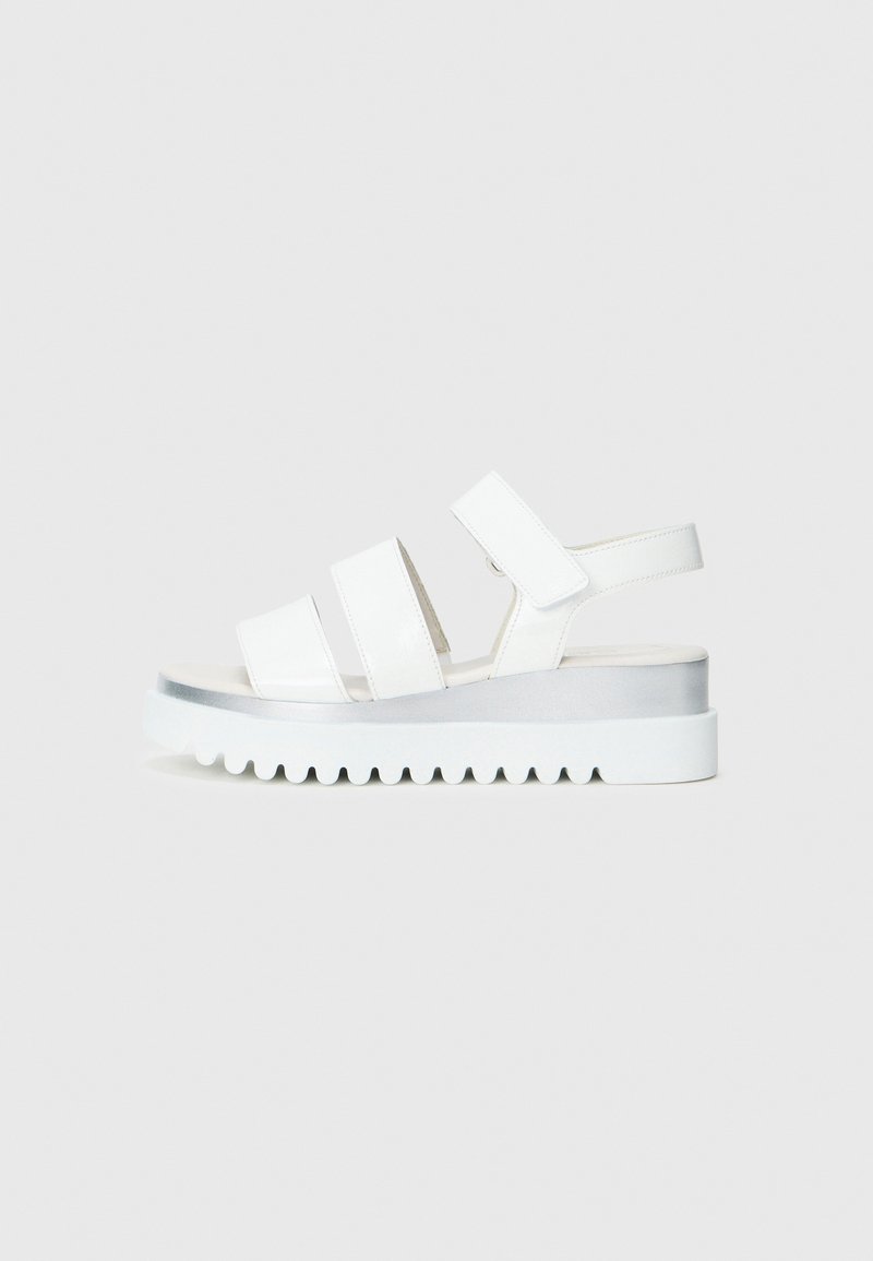 Sandalias de plataforma blancas con tres correas anchas, suela texturizada y un detalle plateado en el tacón. Fabricadas en material sintético.