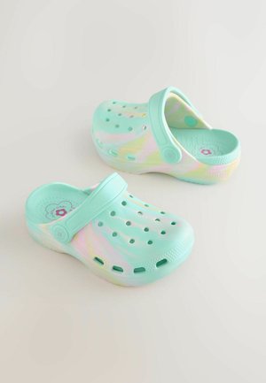 Zuecos de un verde menta claro con un acabado texturizado, que presentan agujeros de ventilación y una correa en el talón. Material liso y brillante con acentos en tonos pastel.