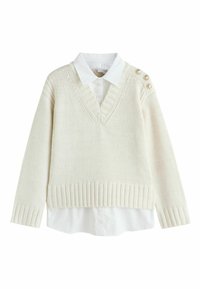 Fehér kötött pulóver V-nyakkivágással, bordázott szegéllyel és mandzsettával, fehér galléros ing felett viselve, három gombbal díszítve.