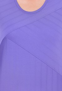 Lilla top med rund hals, struktureret stof med diagonale striber og en glat finish. Designet inkluderer kontrasterende stofsektioner.