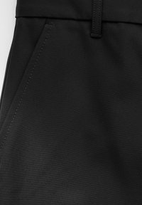 Schwarzer Stoff mit glatter Textur und leichtem Glanz. Verfügt über einen flachen elastischen Bund und seitliche Taschen, mit sauberen Nähdetails.