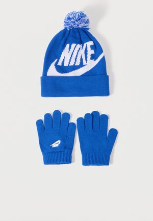 Cappello invernale di maglia blu con pon pon e grande logo Nike bianco, abbinato a guanti di maglia blu con un logo Nike bianco più piccolo su un guanto.