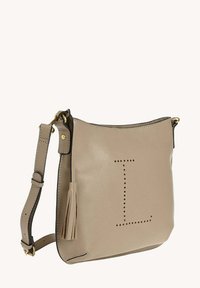 Sac à épaule en cuir beige avec lettre "L" perforée, quincaillerie dorée, bandoulière réglable et un gland décoratif sur le côté.