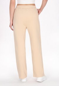 Lysbeige sweatpants med elastisk talje, løs pasform og glat stoftekstur. Skåret til en lige ben med minimal detaljer.