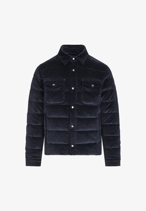 Mørkeblå kordfløyels pufferjakke med knappelukking foran, to brystlommer og spiss krage. Har en quilted tekstur og metallaksenter.