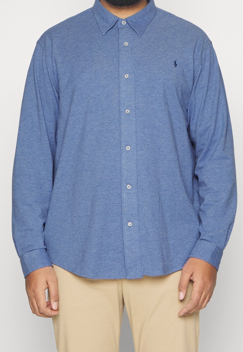 Niebieska koszula zapinana na guziki, wykonana z teksturowanej tkaniny, z klasycznym kołnierzykiem i długimi rękawami, z małym logo na lewej piersi.