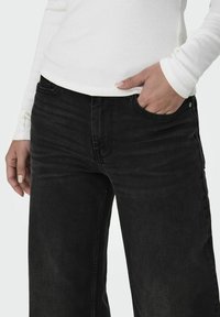 Zwarte denim jeans met een rechte pasvorm, met een klassiek vijf-pocketontwerp en subtiele stikseldetails. Gecombineerd met een wit geribbelde top.