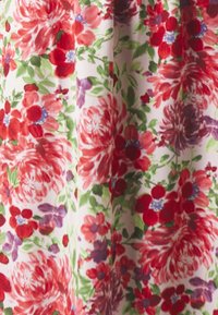 Kukallinen kangas, jossa on suuria punaisia ja violetteja kukkia vihreillä lehdillä vaalealla taustalla; akvarellityylinen, pehmeällä tekstuurilla.
