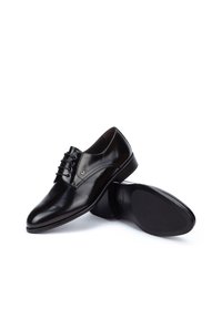 Zapatos de vestir de cuero negro con acabado liso, punta redondeada, silueta arqueada, cordones en la parte delantera y un sutil detalle de marca en el costado.