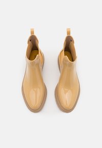 Bottines en cuir brillant couleur fauve avec des bouts ronds, des panneaux latéraux élastiques et des languettes de tirage, présentées en vue du dessus sur un fond blanc.