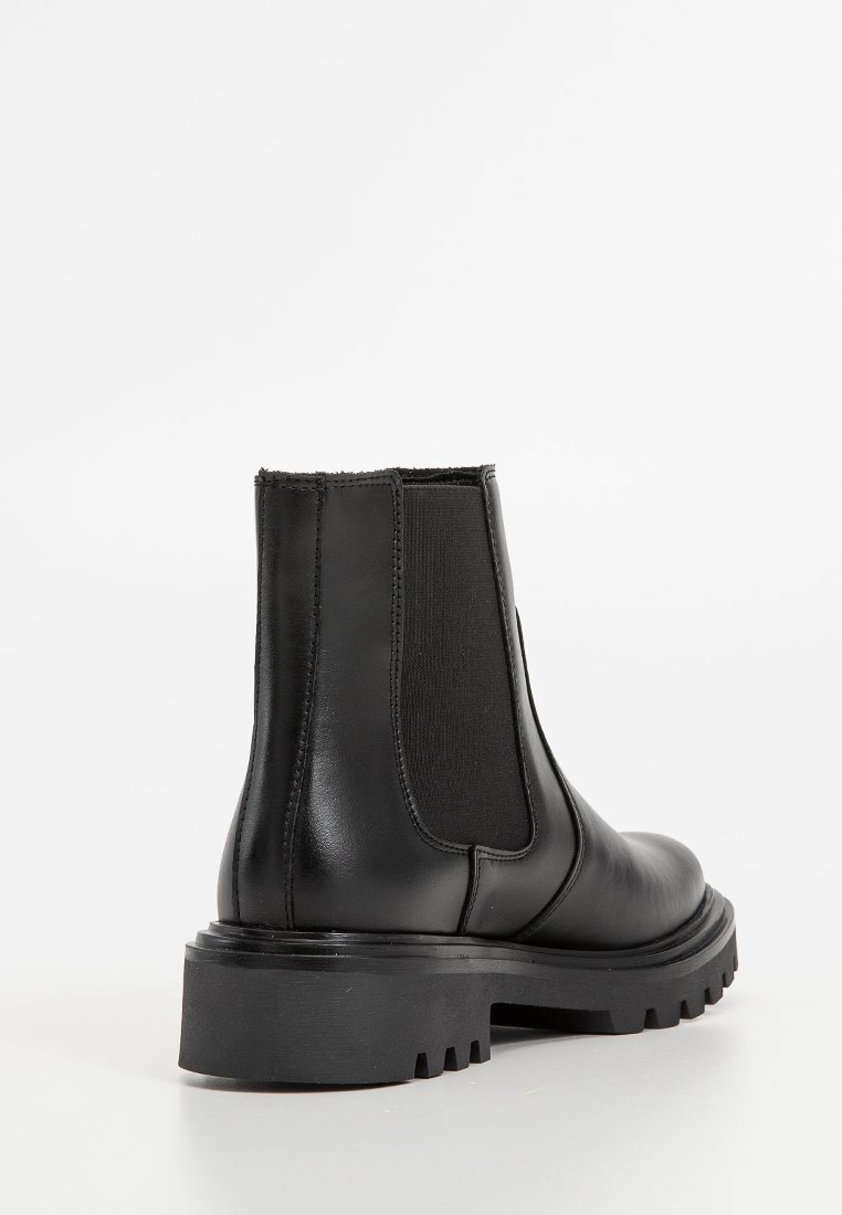 Zwarte Chelsea-boot van gladleer, met elastische zijkanten, een stevige zool en een ronde neus.