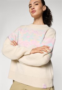 Cremefarbener gestrickter Pullover mit einem geometrischen Pastellmuster auf der Vorderseite und rosa Akzenten an den Ärmeln, mit gerippten Bündchen und Saum.