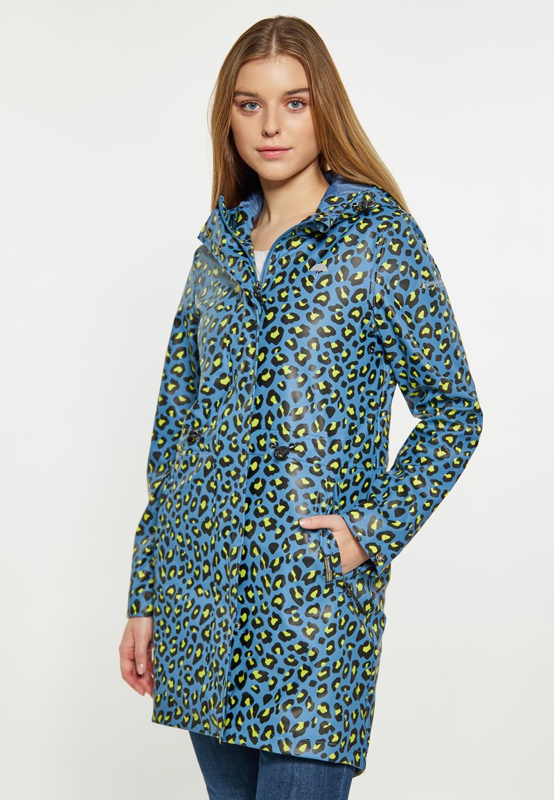 Vandeniui atsparus mėlynas lietpaltis su juodu ir neoniniu žaliu leopardų raštu, turintis gobtuvą, užtrauktukus kišenėse ir reguliuojamą raištelį juosmenyje.