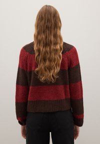 Pull en tricot avec des rayures horizontales marron foncé et rouge, présentant une texture côtelée et un design cropped. Manches longues et encolure ronde.