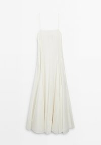 Longue robe blanche sans manches avec des bretelles spaghetti et une jupe fluide plissée suspendue sur un fond uni.