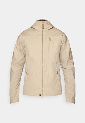 Veste légère beige avec un col montant, fermeture éclair à l'avant et deux poches zippées. Tissu lisse avec un minimum de détails de couture.