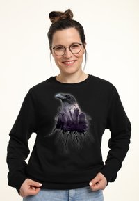 Černá mikina s velk�ým grafikou havrana v purpurových a šedých tónech, složitými detaily a kořenovou symbolikou na spodní části.