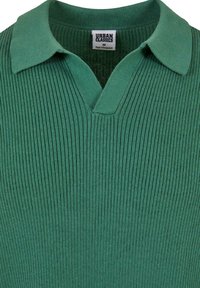 Grønn rippet polo skjorte med V-hals, kontrastkrage og "URBAN CLASSICS" merke, laget av et strukturert strikkemateriale.