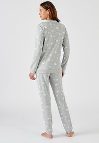 Conjunto de pijama gris de tejido suave, con un patrón impreso de pájaros blancos. Parte superior de manga larga y pantalones elásticos con puños en los tobillos.
