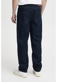 Pantalones vaqueros de mezclilla azul oscuro con corte recto, que cuentan con dos bolsillos traseros, costuras visibles y una etiqueta de cuero en la cintura.