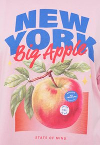 Ροζ μπλουζάκι με γραφικό από ροδάκινο με πράσινα φύλλα, έντονο κείμενο "NEW YORK Big Apple" και κυκλικά μπλε και λευκά αυτοκόλλητα.