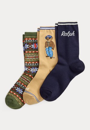 Tre par ankelstrømper: grønne med rødt og blåt mønster, beige med en bjørn iført jakke og kasket, og marineblå med teksten "Ralph" og hvide striber på kanten.