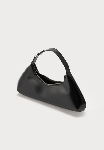 Sac à main triangulaire en cuir noir avec une seule bandoulière et une fermeture éclair argentée partiellement ouverte sur un fond clair uni.