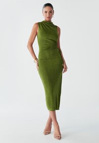 Robe midi verte sans manches avec col montant, détail froncé sur le côté et texture lisse. Accentuée d'un lien latéral pour ajuster la coupe.