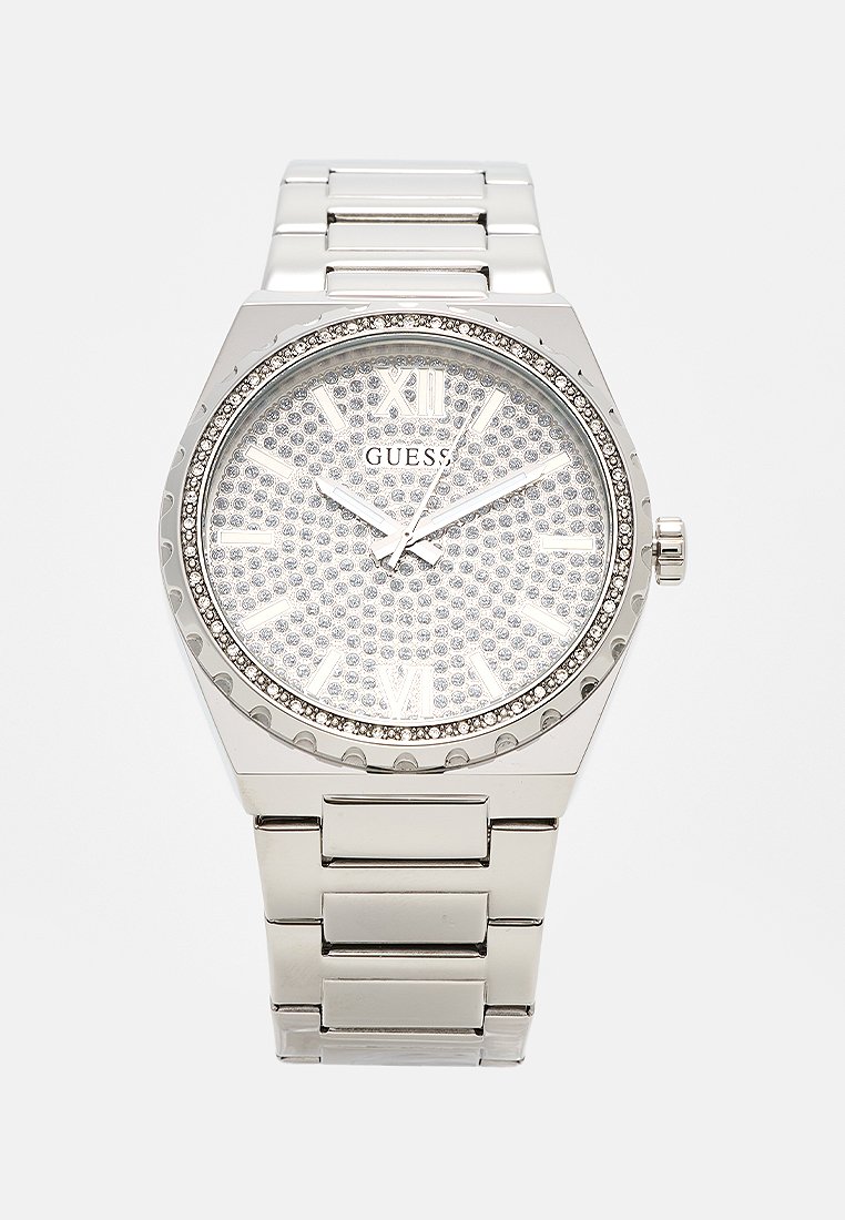 Orologio in metallo argentato con quadrante rotondo, decorato con cristalli; presenta numeri romani e un movimento a tre lancette. Cinturino in acciaio inossidabile.