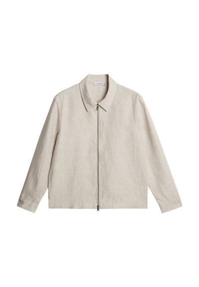 Μπεζ μακρυμάνικο μπουφάν με μυτερό γιακά και ολόκληρο φερμουάρ μπροστά, φτιαγμένο από υφασμάτινη υφή.