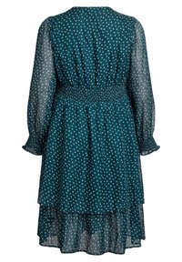 Tirkizna haljina s nabranim pojasom, prozirnim dugim rukavima i višeslojnim donjim dijelom; sadrži uzorak točkica po cijeloj haljini. Lagan materijal.