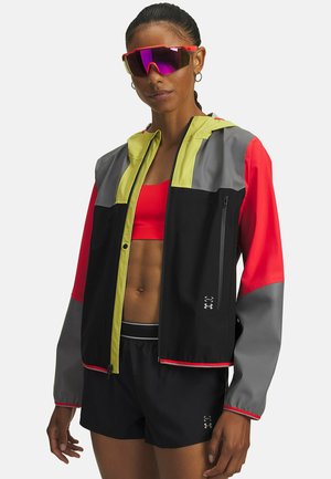 Veste légère à capuche avec des panneaux noirs, rouges, gris et jaunes fluorescents. Texture lisse avec fermeture éclair à l'avant et détail du logo.