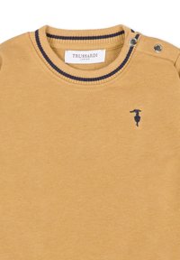 Maglione di cotone giallo con collo a costine blu navy, dotato di bottoni sui lati delle spalle e un piccolo logo ricamato blu sul petto.