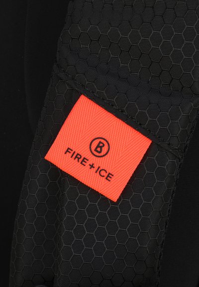 Schwarzer Stoff mit einem Wabenmuster, versehen mit einem leuchtend orangefarbenen Etikett, das "FIRE+ICE" in schwarzer Schrift trägt. Strukturelle Oberflächendetails sichtbar.